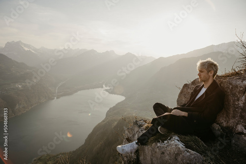 Young man sitting on rocky mountain photo