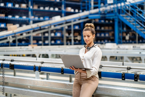Woman using laptop in warehouse photo