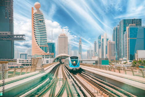 Obraz na płótnie Monorail Subway train rides among glass skyscrapers in Dubai. Traffic on street in Dubai. Cityscape skyline. Urban background. Altered sky. w salonie