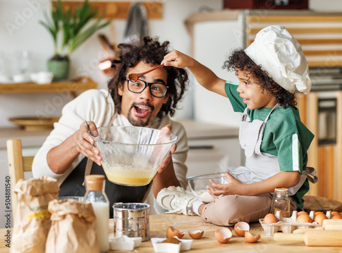 Foto Black father and child making batter in kitchen