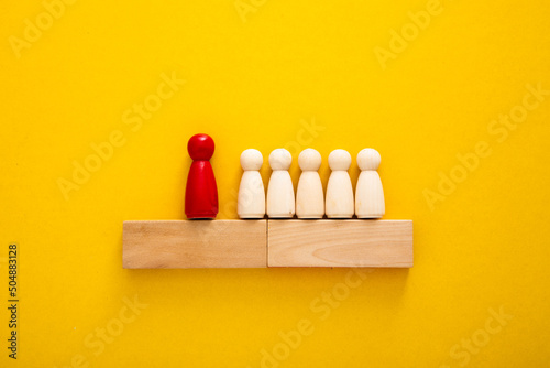 Concept of supremacy leader. Wooden figures on yellow background