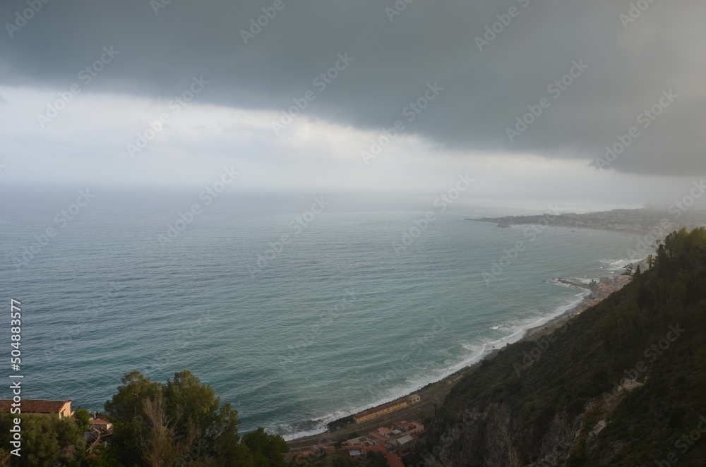 The beautiful sea surrounding Sicily on a cloudy day with waves crashing against the rocks