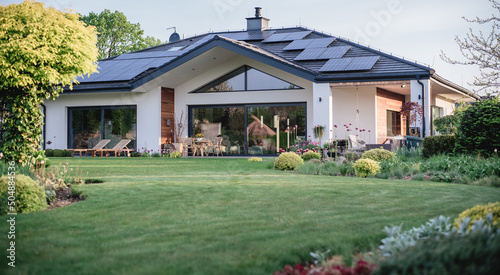 Nowoczesny parterowy dom z dużymi oknami fotowoltaiką i pięknym zadbanym trawnikiem