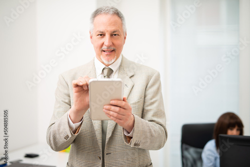 Senior businessman using a tablet in his office