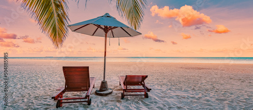 Fototapeta Naklejka Na Ścianę i Meble -  Beautiful tropical sunset beach. Romantic couple goals, two sun beds, umbrella under palm tree leaves. Panoramic coast landscape, love and relaxation banner. Colorful dream travel sea sand sky island 