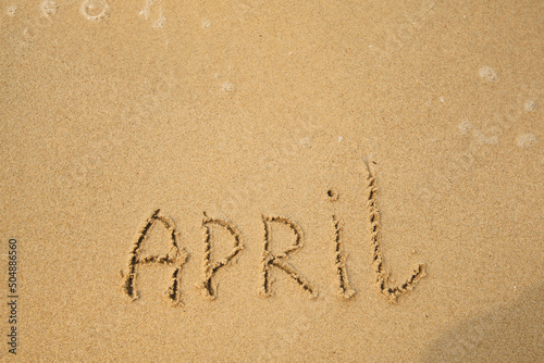 April - drawing handwritten on the sea beach sand.