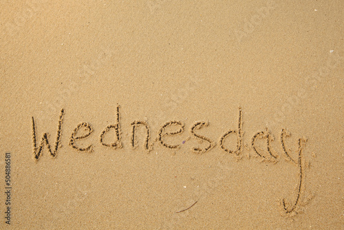Wednesday - drawing of days of the week, handwritten on the sea beach sand.