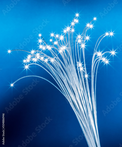 Fototapeta Naklejka Na Ścianę i Meble -  Bundle of optical fibers with lights in the ends. Blue background.