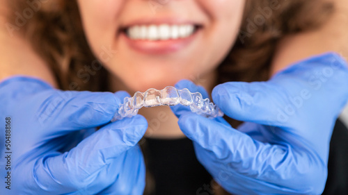 Foto Orthodontist doctor putting silicone invisible transparent braces on woman teeth