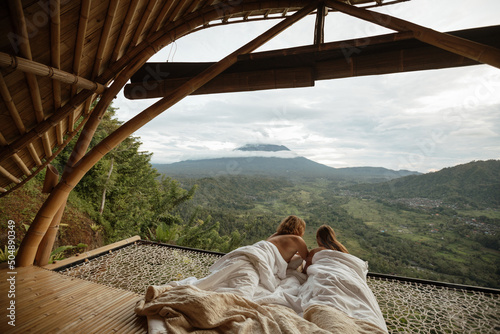 Couple in love covering a white blanket lying in a hammock at the view of nature of mountains with green jungle. travel in the morning time with mountain view and natural green view feeling chill
