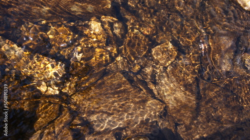 Flowing transparent water with a rocky bottom