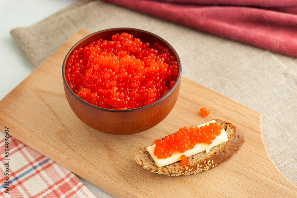 Red salmon caviar in a Japanese cup. Coho salmon caviar on a piece of