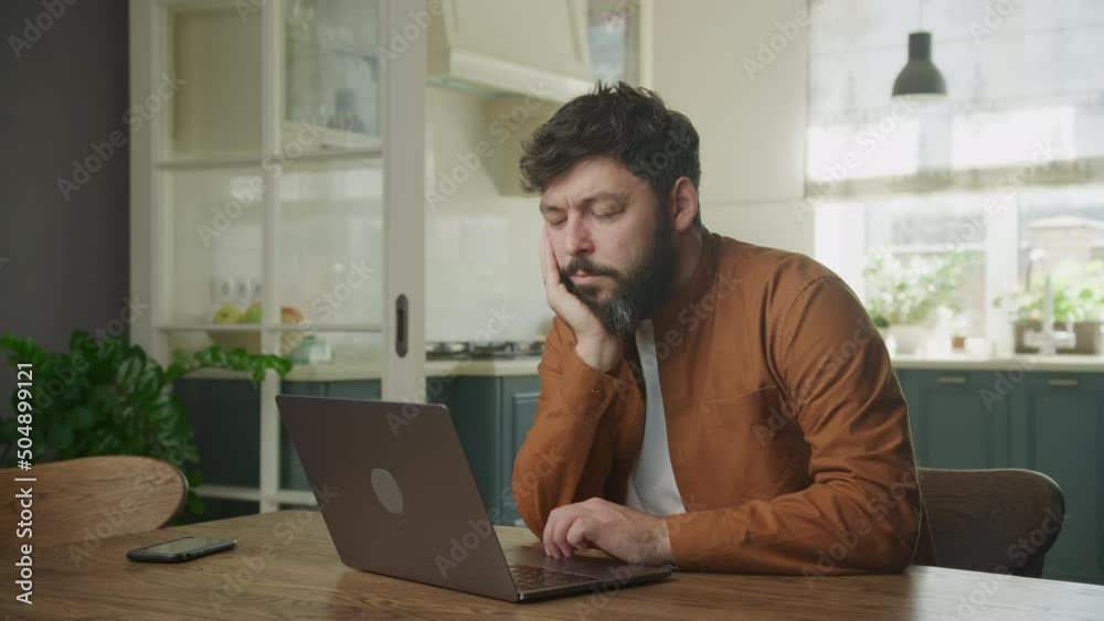 Young adult enterpreneur bored browsing on a laptop indoors