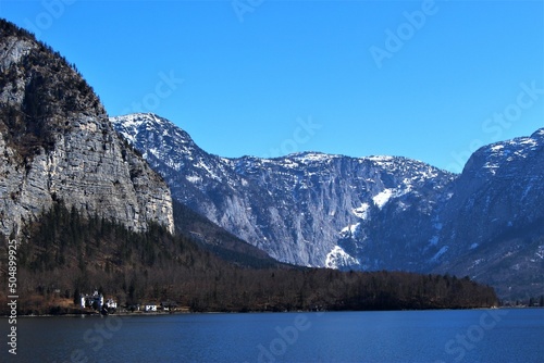 Alpine mountain lake on a cloudless day in winter. Lack of snowfall in the alps from climate change example (Lake Hallstatt, Austria)