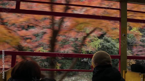 KYOTO, JAPAN - DECEMBER 2021 : View of riding on Sagano Romantic train (Sagano Scenic Railway) in Autumn leaves season. Saga torokko station to Kameoka torokko Station. photo