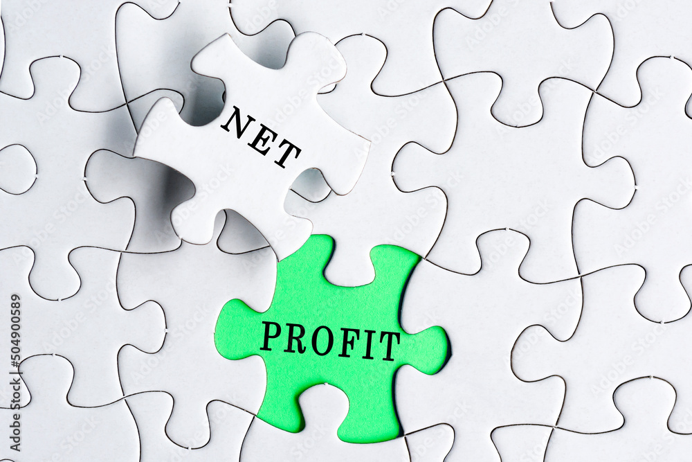 White jigsaw puzzle with word net profit over green background. White jigsaw puzzle with word net profit over green background.