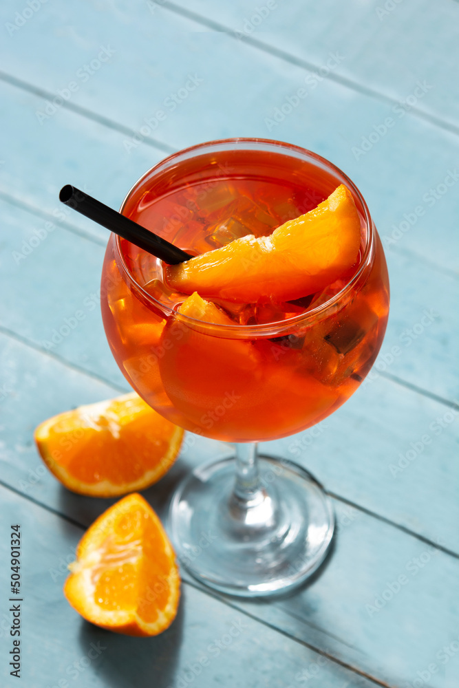 Glass of aperol spritz cocktail on blue wooden table - obrazy, fototapety, plakaty 
