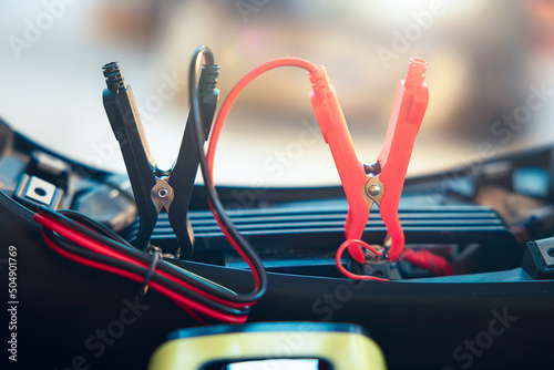 Charging electric power, energy to accumulator or dead battery in breakdown motorcycle for start. Include equipment tool i.e. portable trickle charger, positive negative clamp, red black cable wire.
