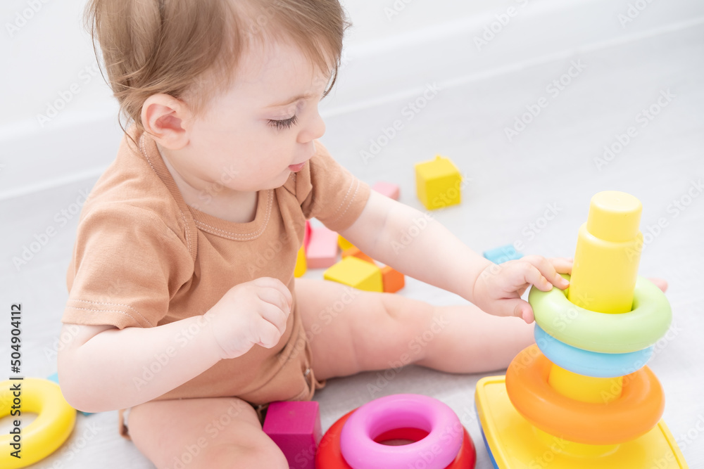 cute baby girl playing with pyramid and wooden toys at home. early children development cute baby girl playing with pyramid and wooden toys at home. early children development