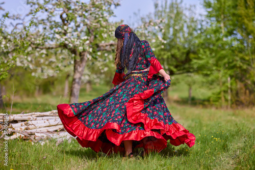 beautiful woman in traditional gypsy dress posing in nature in spring