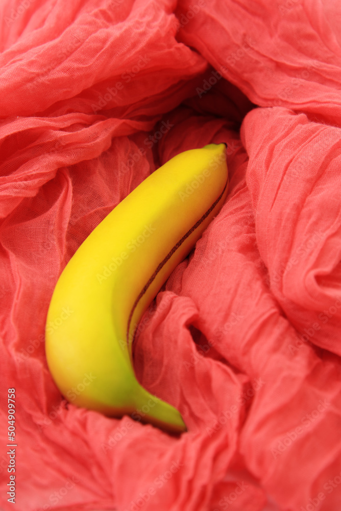 Sexy concept with banana on pink textile. Selective focus.