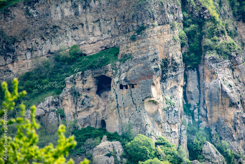 Cave in the mountains. Steep cliffs and a cave with trenches and rooms