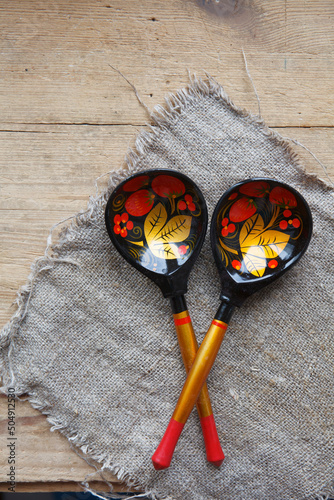 Russian folk background with Khokhloma painting spoons on wooden table and burlap, canvas. Space for text photo