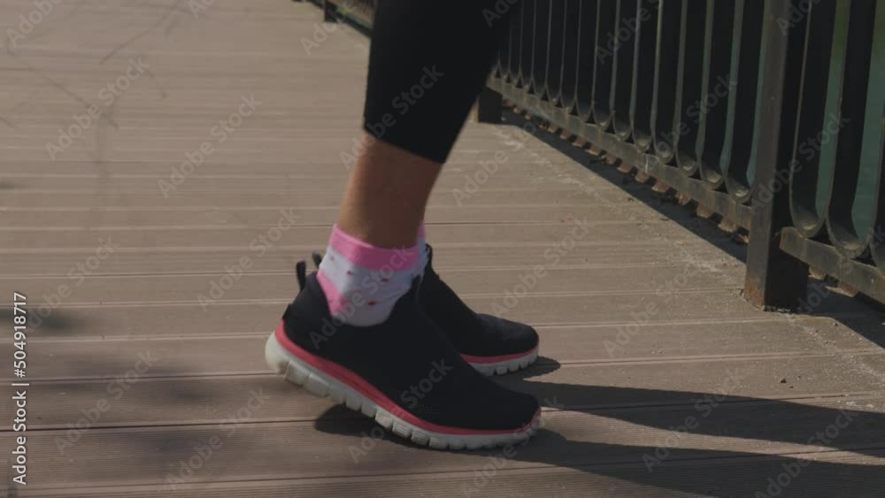 legs in black pink snickers warming up on wooden path in park, feet rotation exercises, close-up. concept of healthy lifestyle, sport outdoors, working out fresh air, steps nft finances, money concept legs in black pink snickers warming up on wooden path in park, feet rotation exercises, close-up. concept of healthy lifestyle, sport outdoors, working out fresh air, steps nft finances, money concept