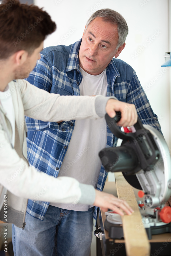 young apprentice cutting wooden plank with a circular saw young apprentice cutting wooden plank with a circular saw