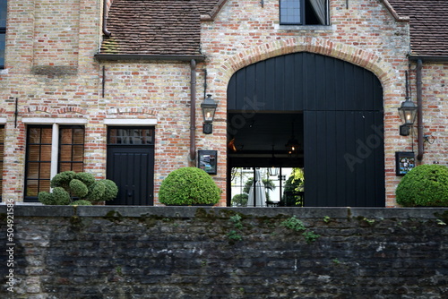 Altes Gutshaus aus Backstein und Naturstein mit großem alten Holztor mit Kaimauer  am Kanal in der Altstadt von Brügge in Westflandern in Belgien photo