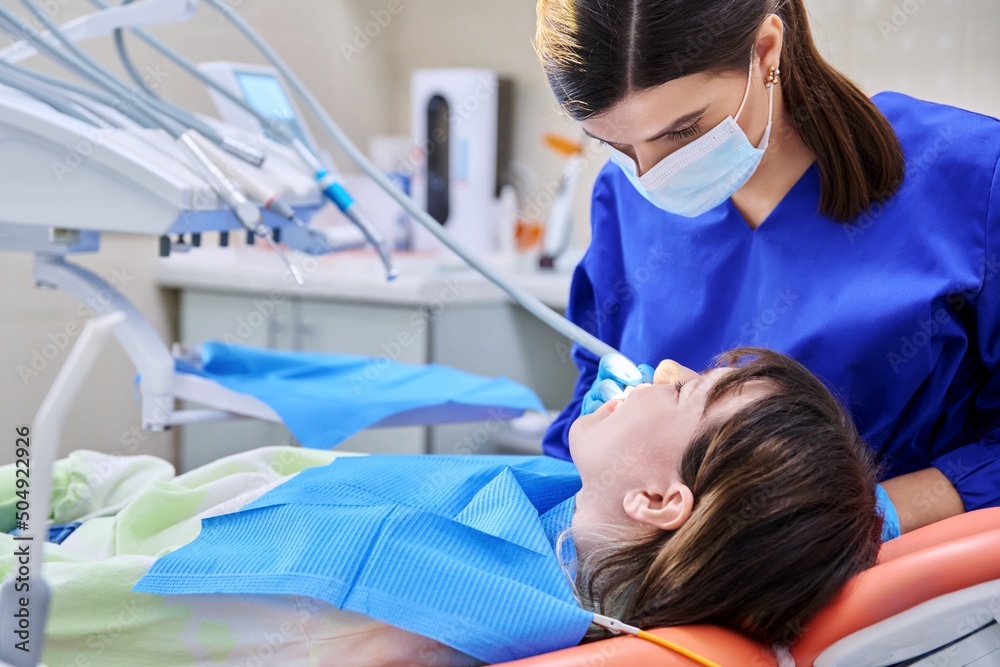 Fototapeta premium Doctor dentist treats teeth to a young teenage female patient