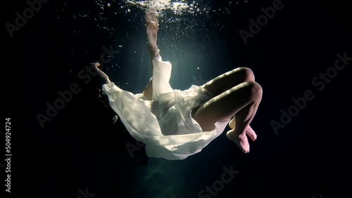 a girl in a white dress under the water mysteriously hangs in the rays of the sun as in a fairy-tale dream