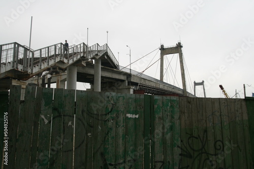 a lone traveler on a stepped staircase climbs a pedestrian bridge in Kyiv