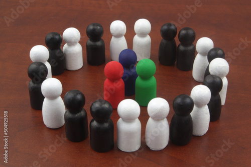 Three colored wooden figures as leaders surrounded by black and white figures. Concept of business leadership. © Valerii Evlakhov