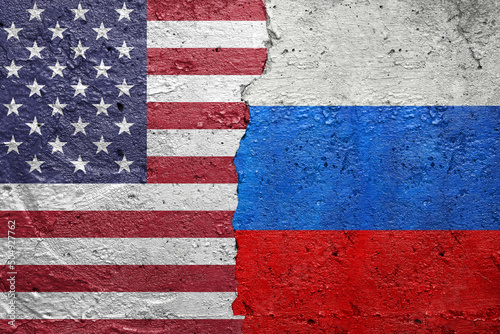 United States of America vs Russia - Cracked concrete wall painted with a USA Americas flag on the left and a Russian flag on the right stock photo