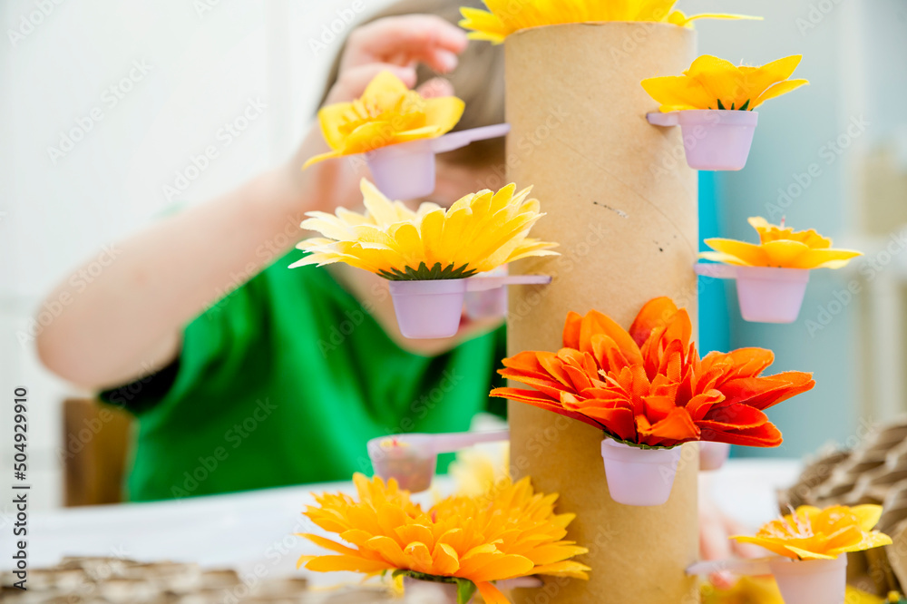 Boy is playing with artificial flowers, bees and a paper
