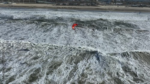 Kite surfer catching large air in murky storm water waves at Scheveningen; drone photo