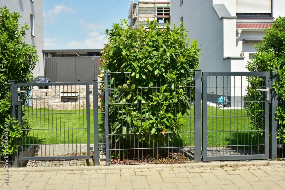 Obraz na plátně Verzinkter Stahlgitterzaun als Einfriedung um den Garten eines Einfamilienhauses