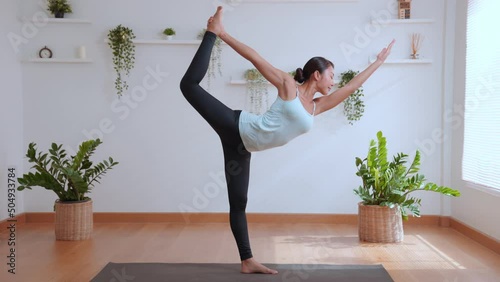 Yoga class at home, happy of young asian woman practicing yoga stretching in Lord of the Dance pose, Yoga and meditation have good benefits for health and wellness. Fitness, sport and healthy concept