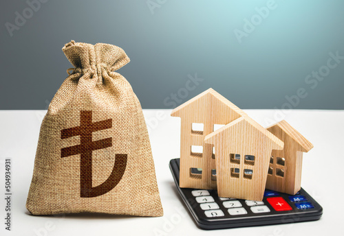 Houses on a calculator and turkish lira money bag. Buying and selling. Real estate valuation. Building maintenance. Mortgage loan. Utilities and services expenses. Taxes. Realty or rental business. photo