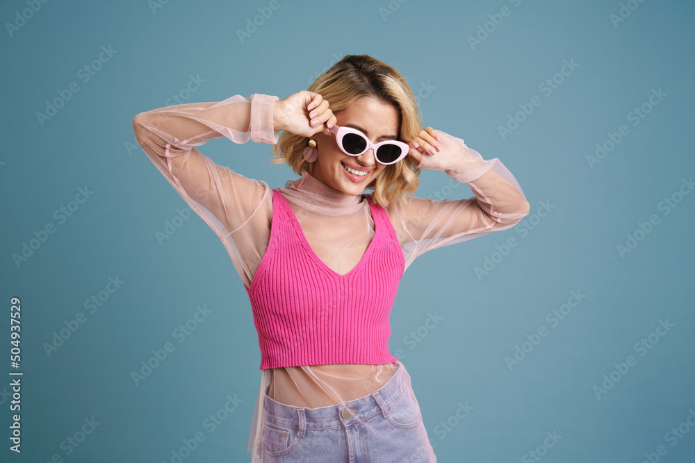Young white woman in sunglasses smiling while posing on camera Young white woman in sunglasses smiling while posing on camera