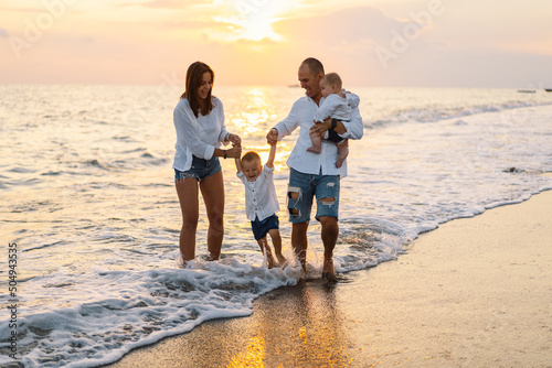 Happy family having fun playing beach in summer vacation on the beach. Happy family and vacations concept. Seascape at sunset with beautiful sky. Family on the beach.