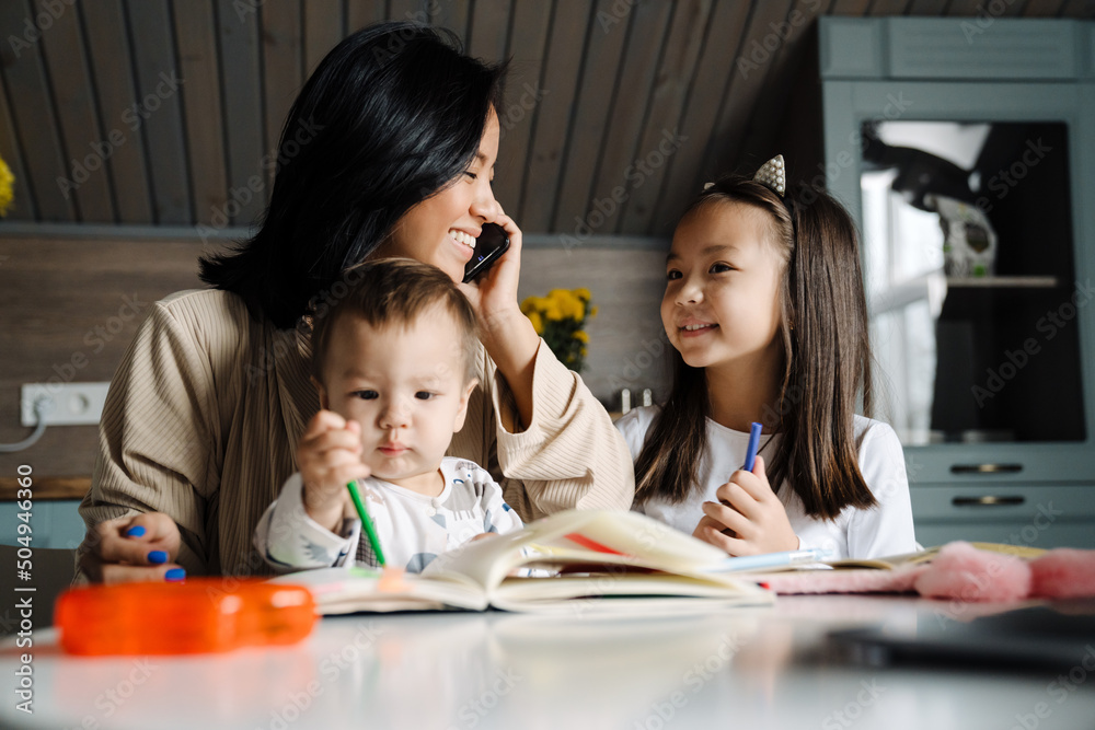 Happy mother talking on cellphone while spending time with her children Happy mother talking on cellphone while spending time with her children