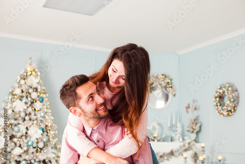 Young happy couple have fun and huggingnear christmas tree © oksix