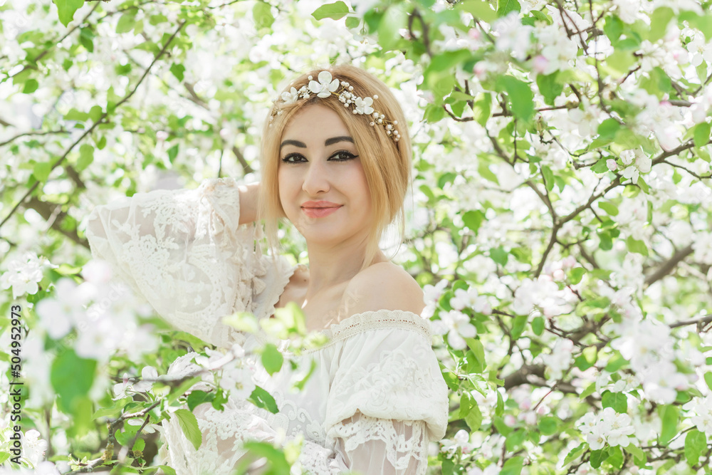 Fototapeta premium Bride at spring garden. Beautiful mix race lady in romantic lace dress with make up and flower wreath