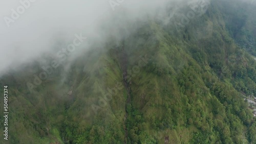 Misty environment with lush green mountainside at caldera lake Batur, aerial photo