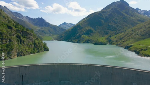Water dam and reservoir lake in Swiss Alps generating hydroelectricity. Aerial view of arch dam between mountains. Hydropower green energy for sustainable development against global warming. Zero CO2