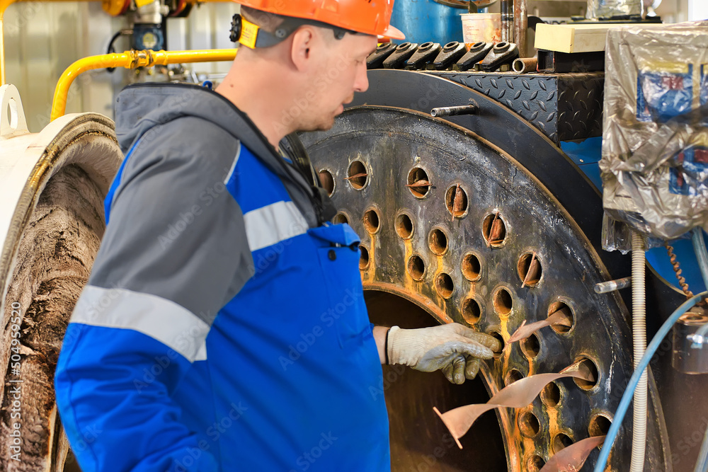Φωτογραφία Engineer in helmet inspects and repairs gas equipment of boiler room