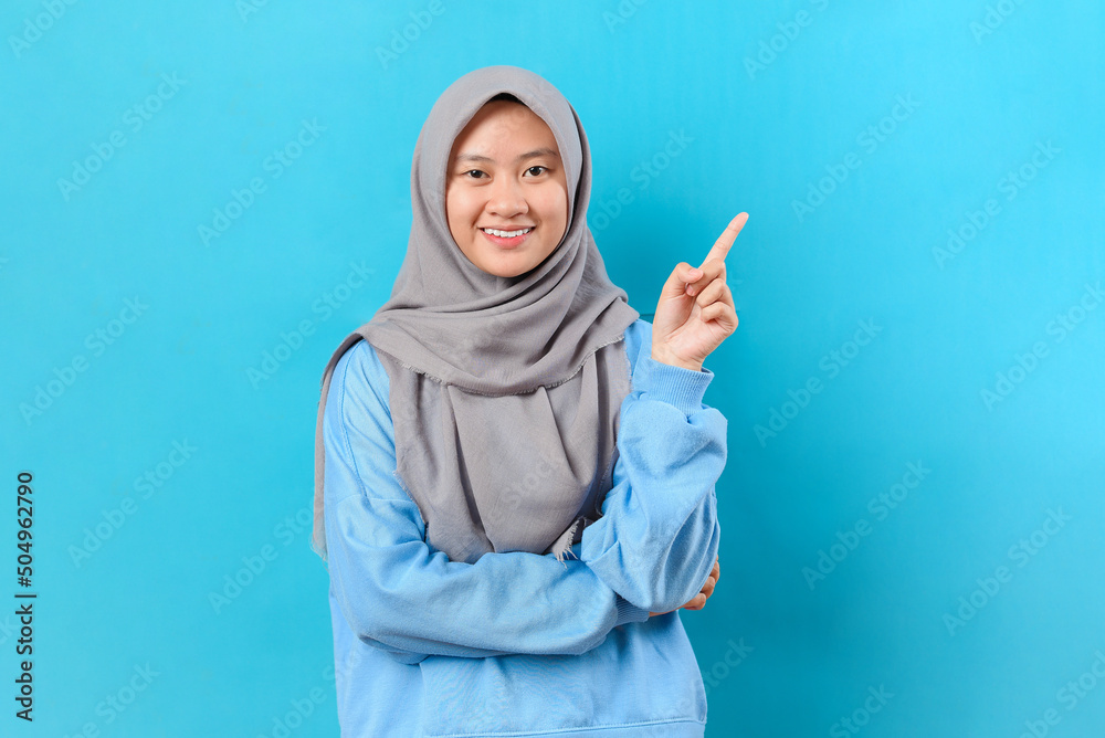 Happy young Asian woman pointing at copy space Happy young Asian woman pointing at copy space