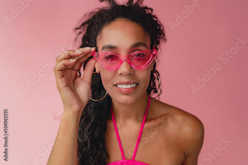 attractive black african american woman in stylish outfit on pink background